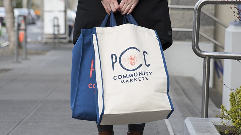 Person holding PCC Community Markets bag.