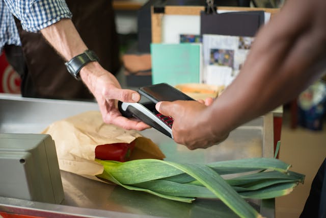 Person uses point-of-sale system to checkout groceries using a cell phone. 