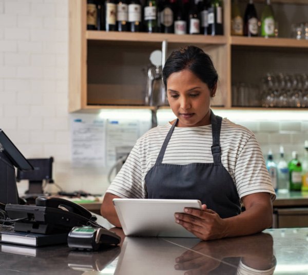 Woman using tablet while at a checkout counter of restaurant.