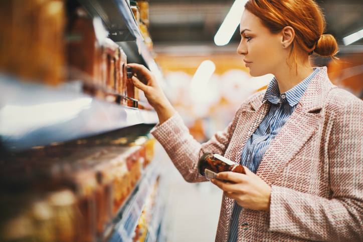 Woman looking at items on a shelf at a grocery store.