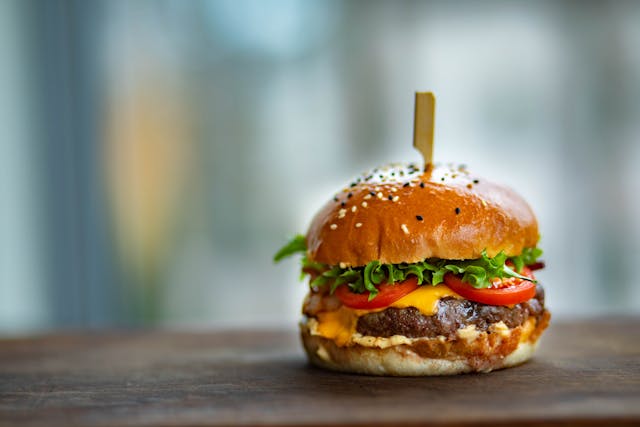 Burger on a table with a toothpick going into it.