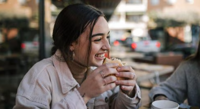 Woman enjoying sandwich outside.