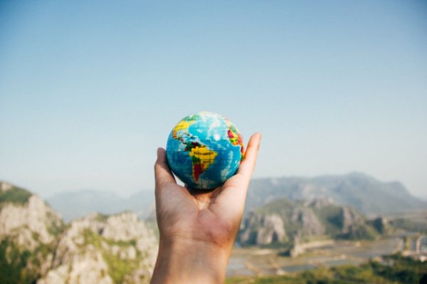 Person holding globe in mountains