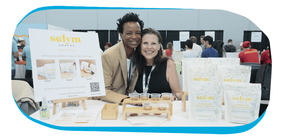 Attendees and an exhibitor smiling